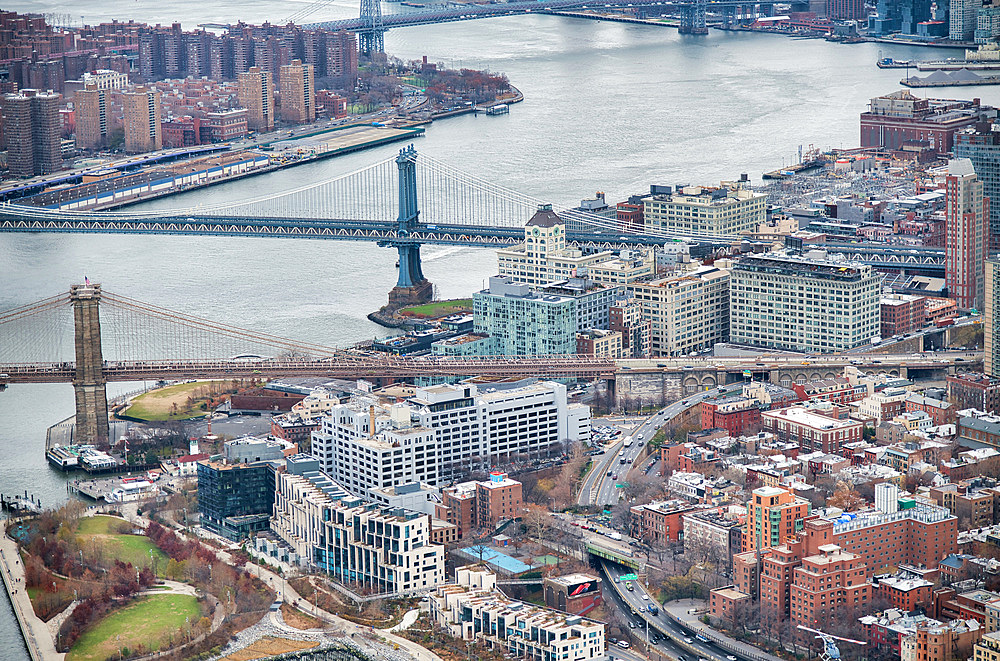 New York City from helicopter point of view. Brooklyn and Manhattan Bridges with Manhattan skyscrapers on a cloudy day.