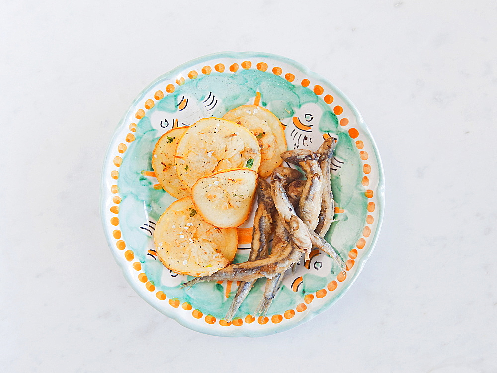 Fried anchovies and lemon in a plate of decaorated ceramic produced by Solimene in Vietri sul Mare village, Cetara, Amalfi coast, Campania, Italy, Europe