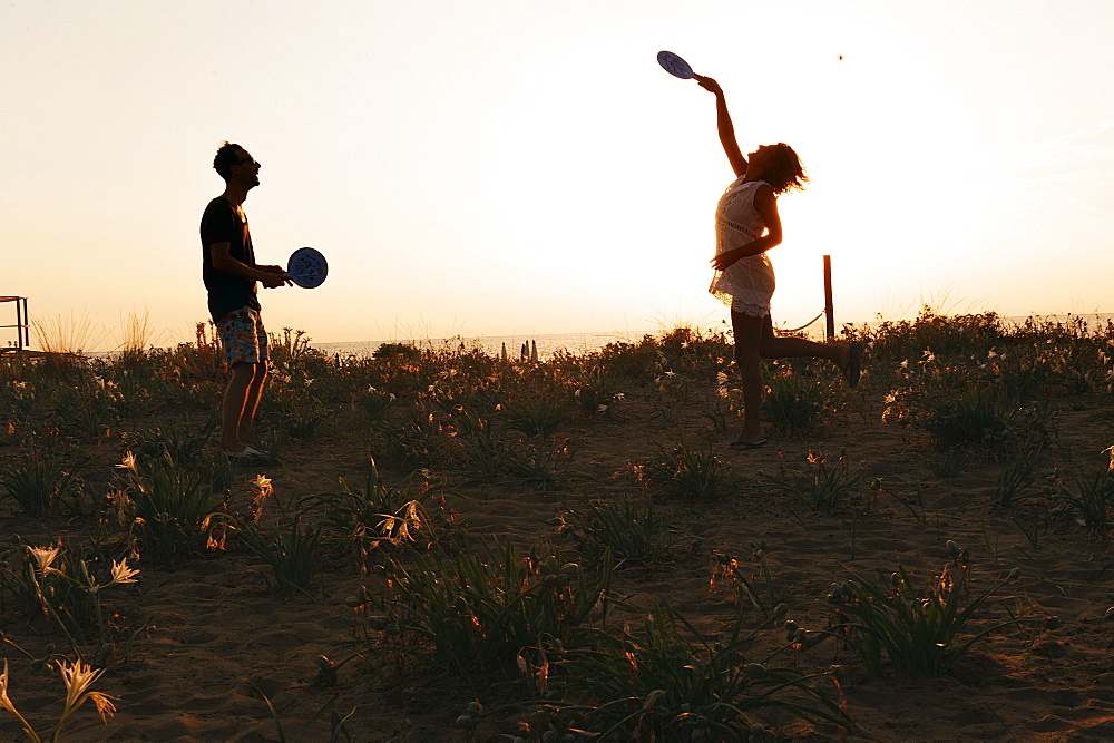 Boys playing racket ball at sunset on the beach, EcoVillage Maremirtilli, Capaccio Paestum, Campania, Italy, Europe