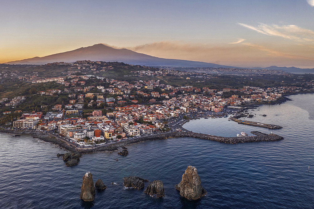 Aerial view of Acicastello and the stacks of Acitrezza, in the background the Etna Volcano, Sicily, Italy, Europe