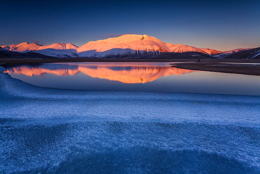 Beautiful landscape in Castelluccio di Norcia during a frozen sunset on Mount Redentore reflected in the lake, Umbria, Italy, Europe