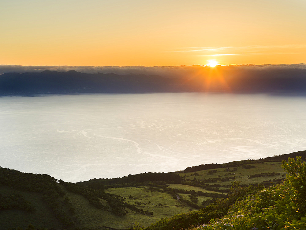 Sunrise over Sao Jorge island. Pico Island, an island in the Azores (Ilhas dos Acores) in the Atlantic ocean. The Azores are an autonomous region of Portugal. Europe, Portugal, Azores