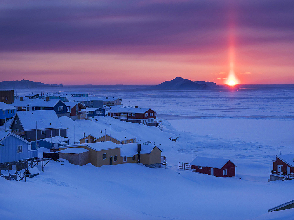 Sunset over icefjord and town. Town Ilulissat at the shore of Disko Bay in West Greenland, center for tourism, administration and economy. The icefjord nearby is listed as UNESCO world heritage. America, North America, Greenland, Denmark