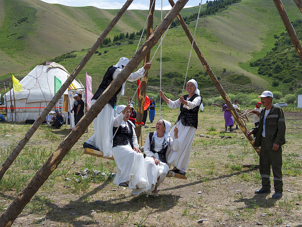 Woman in traditional garb having fun on a swing. Folk Festival commemorating the origin myth the Tien Shan Maral (Tian Shan wapiti), an origin myth of the Kyrgyz tribes. Near Tasch Baschat, Naryn region. Asia, Central Aisa, Kyrgyzstan