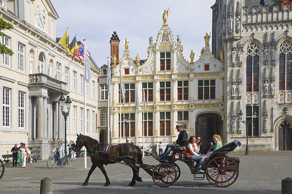 A horse drawn carriage crosses the Burg Square, passing the Stadhuis (Town Hall) buildings, Brugge, Belgium, Europe