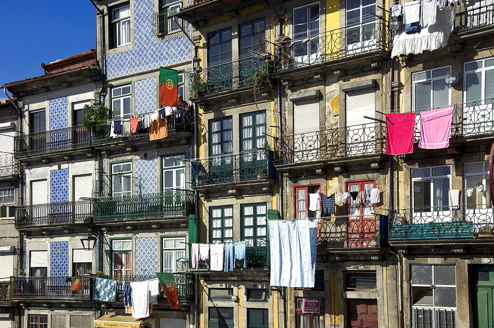 A residential street in the old town with traditional wrought iron balconies, blue and white tiled panels on the outside walls, washing hanging in the sun, Oporto, Portiugal, Europe 