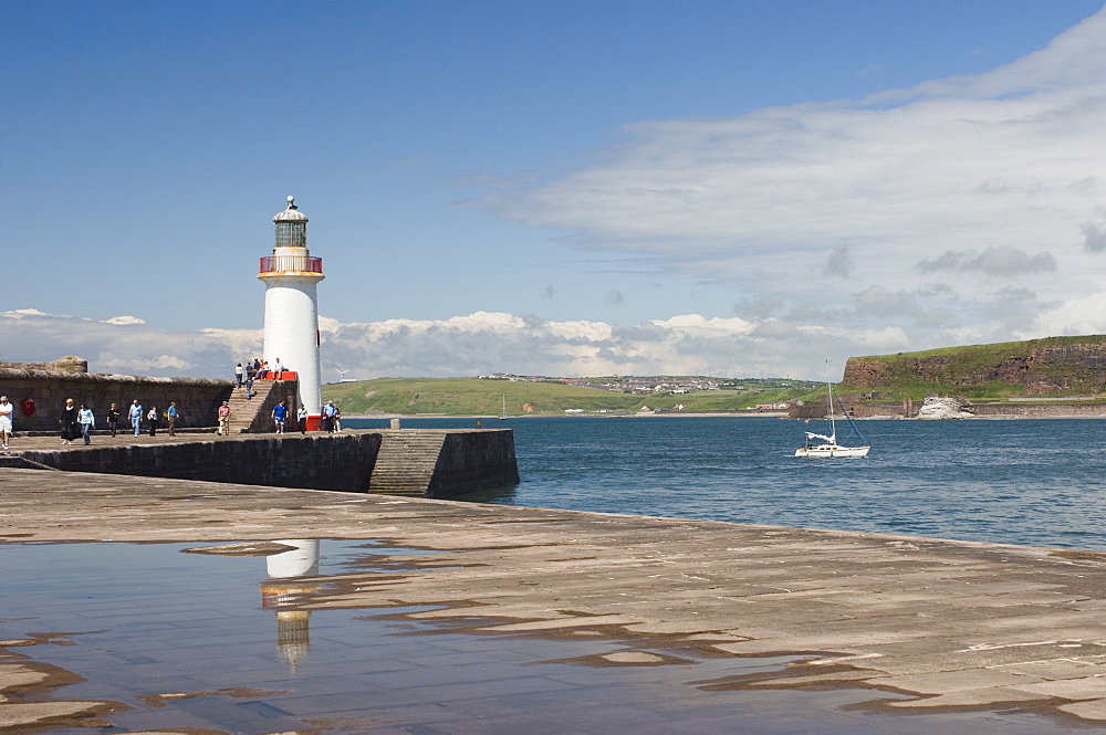 Lighthouse at entrance to outer harbour, motor yacht entering, Whitehaven, Cumbria, England, United Kingdom, Europe