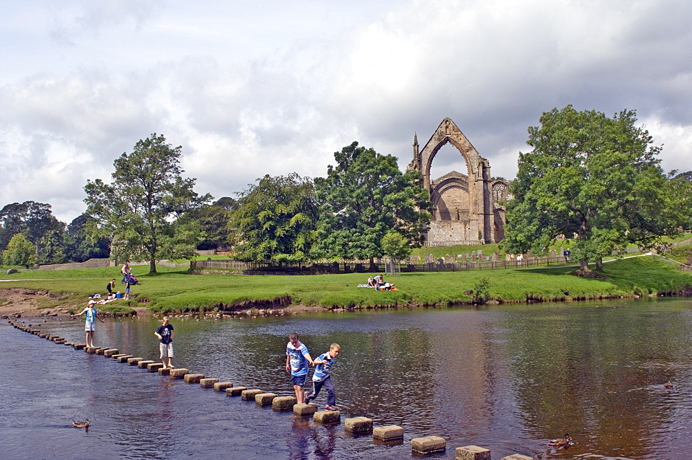 Children crossing the stepping stones across the river Wharfe at Bolton Abbey, Wharfedale, Yorkshire Dales National Park, Yorkshire, England, United Kingdom, Europe