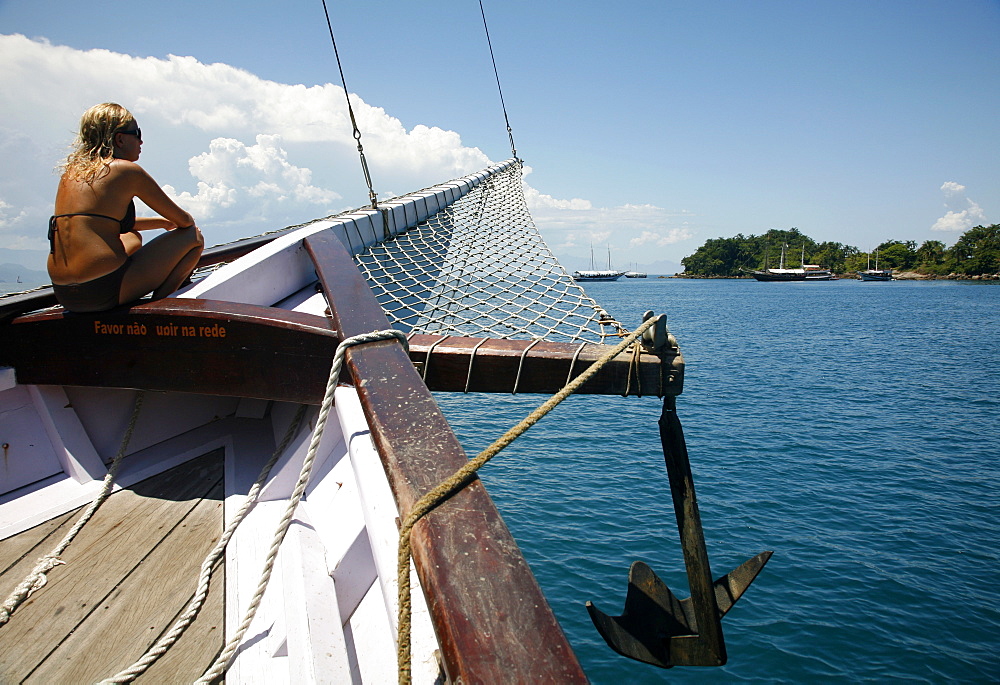 Tourist on a schooner cruising between the different beaches and islands around Paraty (Parati), Rio de Janeiro State, Brazil, South America