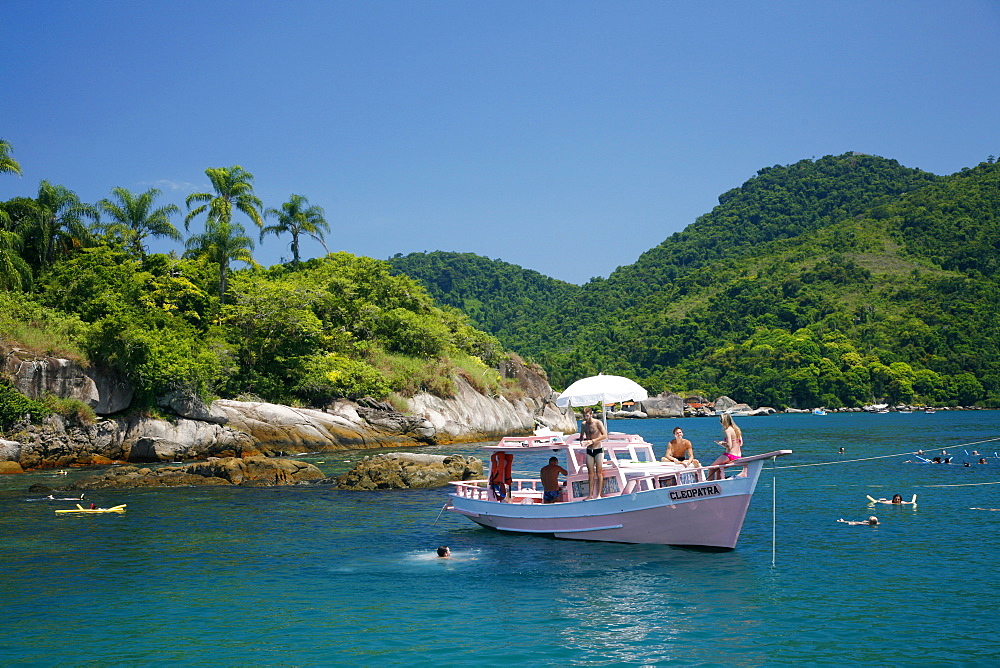 Tourist on a chartered fishing boat cruising between the different beaches and islands around Paraty (Parati), Rio de Janeiro State, Brazil, South America