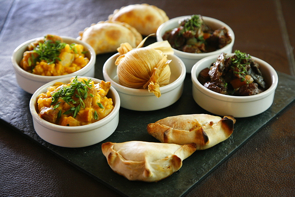 A tray with traditional food from the northwest, including empanadas, locro and humitas, at the restaurant of La Comrca Hotel in Purmamarca, Jujuy Province, Argentina, South America 