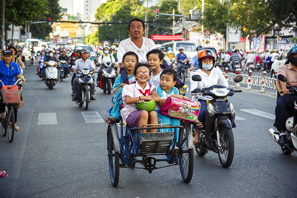 School kids riding a cyclo on a busy street, Ho Chi Minh City (Saigon), Vietnam, Indochina, Southeast Asia, Asia