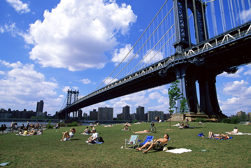 People sunbathing at a park in Brooklyn under the Manhattan Bridge, New York, New York State, United States of America, North America