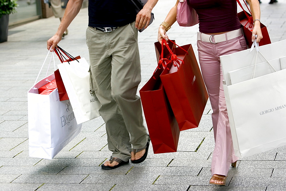 Couple walking with shopping bags on Konigsallee, Dusseldorf, North Rhine Westphalia, Germany, Europe