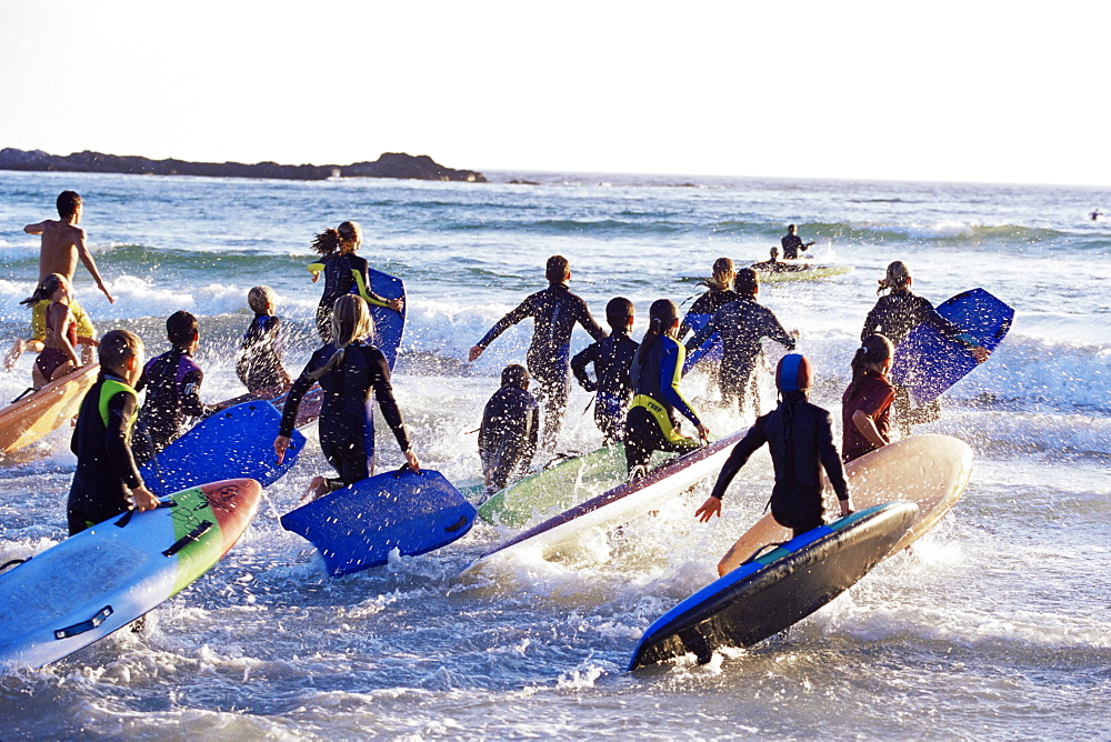 Teenage surfers running with their boards towards the water at a life saving competition, South Africa, Africa