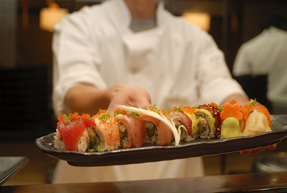 Sushi chef presents a plate of various seafood sushi, Japan, Asia