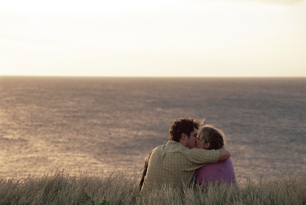 Couple kissing on cliff overlooking Pacific Ocean at South Point, Big Island, Hawaii, Pacific, United States of America, North America