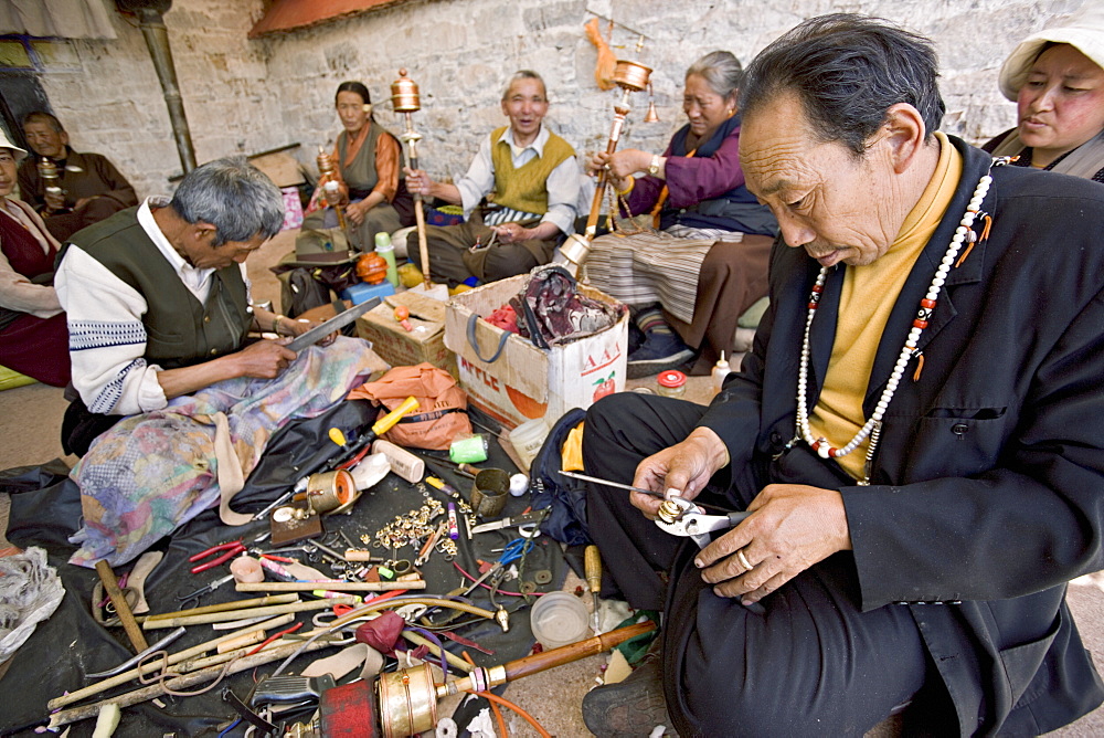 Carrying out routine maintenance of prayer wheels on a monastery roof, Lhasa, Tibet, China, Asia