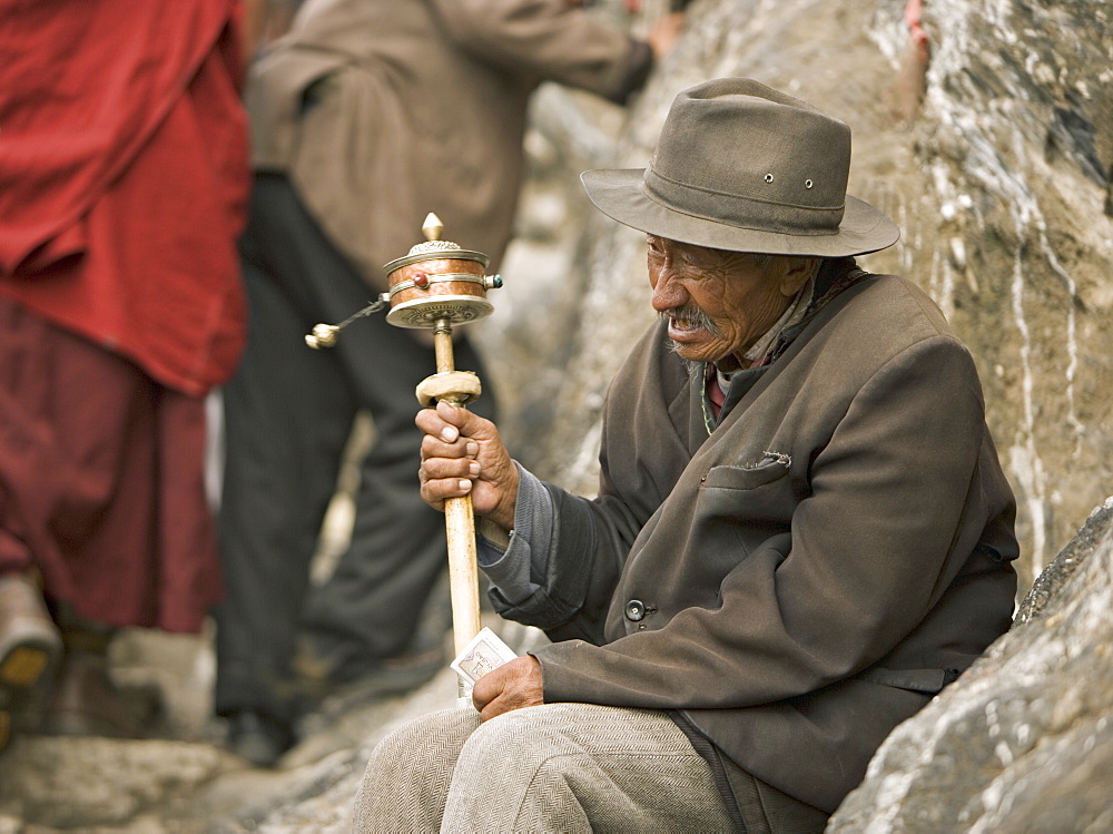 Old man sits, prays and hopes for donations on the Buddhist Lingkhor circuit, a traditional pilgrimage around the holy sites of the city, Lhasa, Tibet, China, Asia