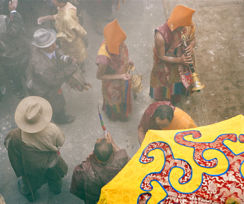 Yellow hat monks at Tibetan Buddhist new year (Lhosar), when flour thrown in the air as part of the celebrations, Samtenling monastery, Bodhnath, Kathmandu, Nepal, Asia