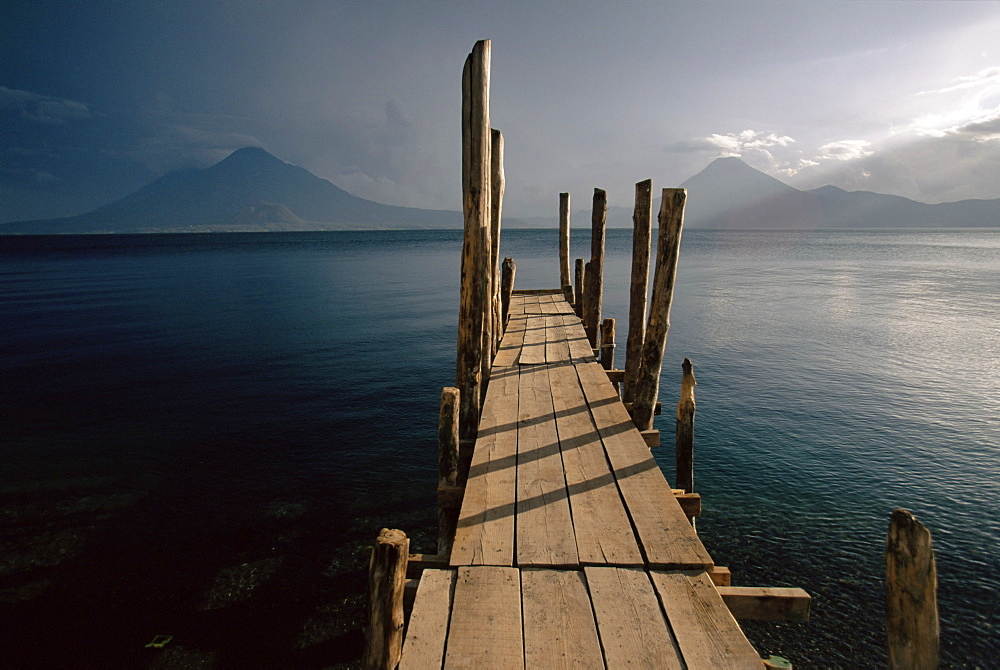 Wooden jetty and volcanoes in the distance, Lago Atitlan (Lake Atitlan), Guatemala, Central America