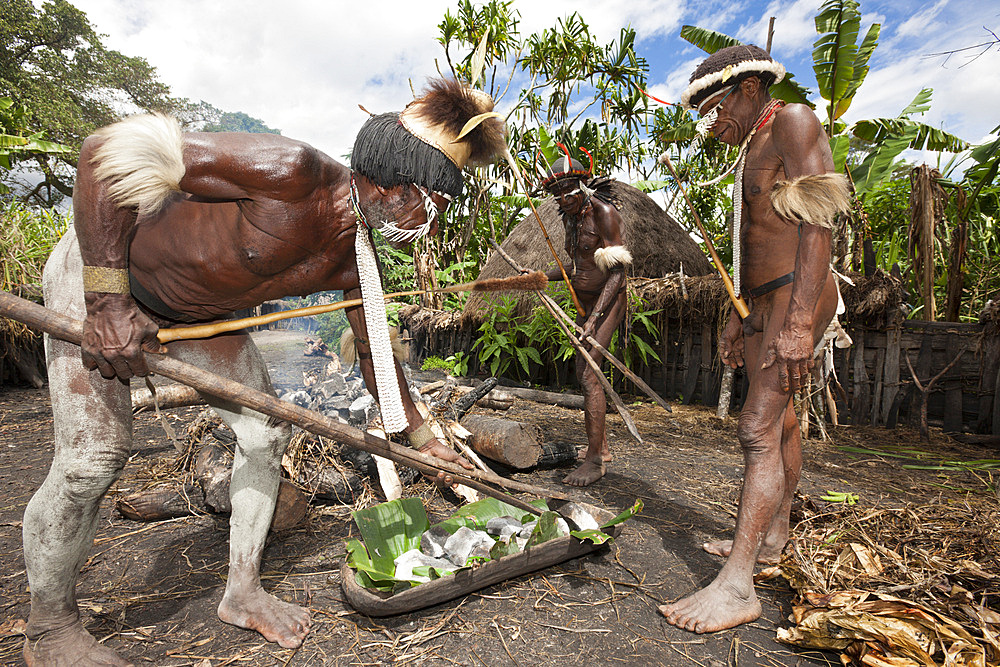 Dani tribesmen heat stones in fire for earth oven, Baliem Valley, West Papua, Indonesia, Southeast Asia, Asia