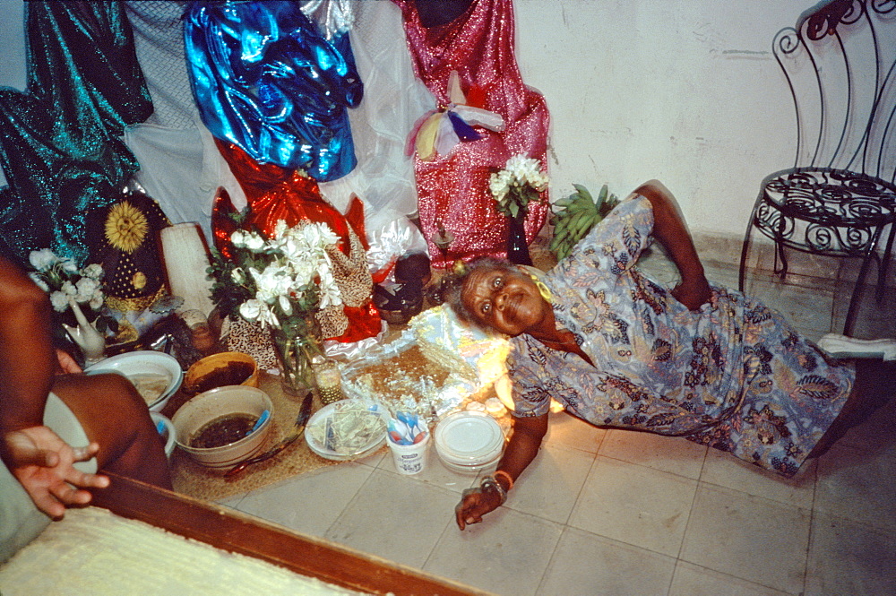 A woman lying down in front of the Santeria altar in her home in the Los Pinos area of Havana, Cuba