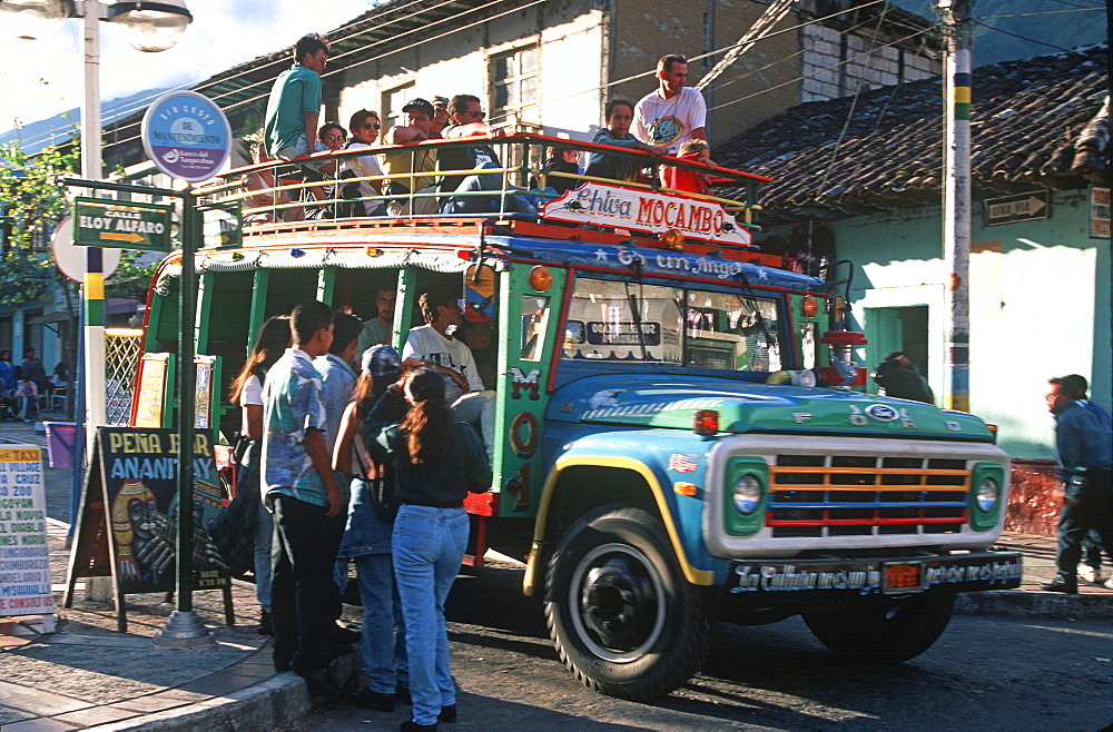 Banos resort and famous hot springs and site of Basilica of Senora de Agua Santa teens on street boarding a local bus, Highlands, Ecuador