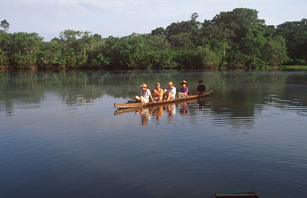 Amazon Basin, Napo River (tributary) La Selva Jungle Lodge, naturalists in dugout canoe on jungle stream in primary rainforest, Amazon, Ecuador