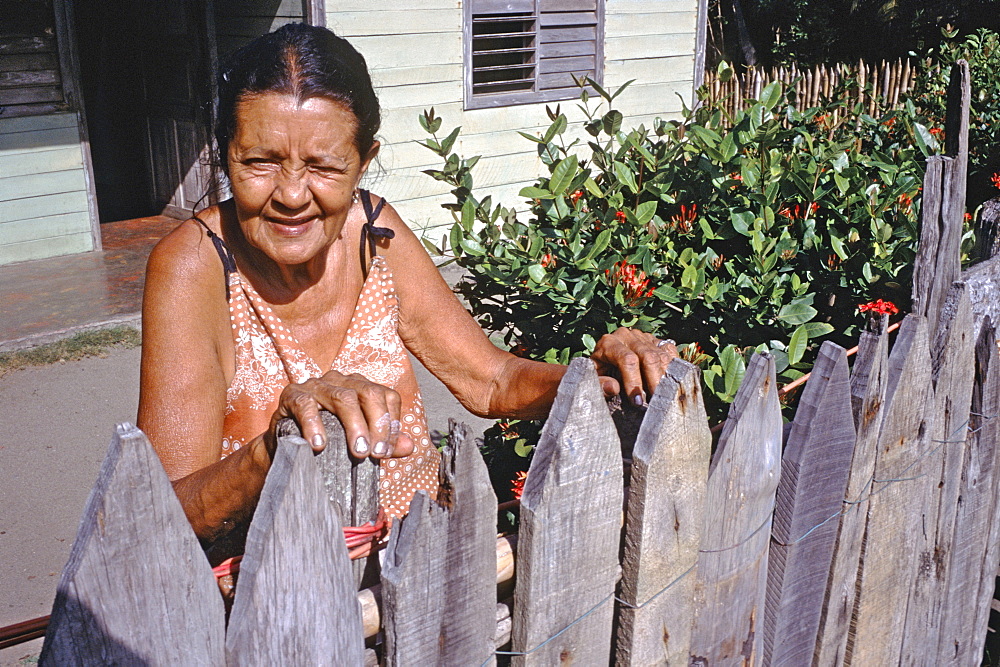 A woman standing in her garden in front of her home located in the rural town of Baracoa in eastern Cuba, Cuba