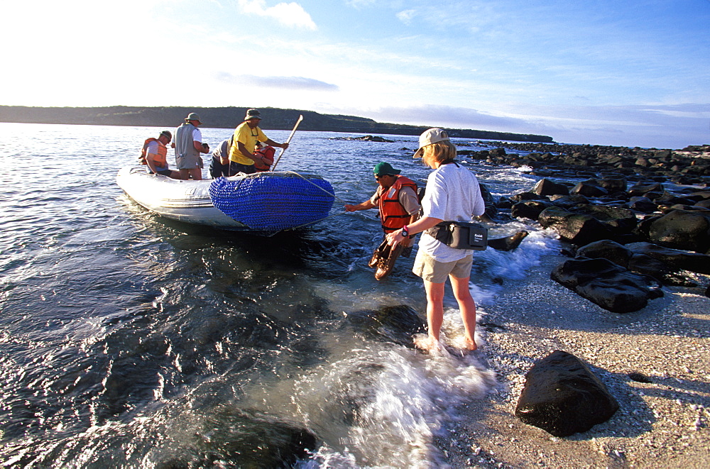 Eco-tourists coming from scuba diving boat for land excursion to see sea lions on Mosquera Island near Bartolome Island, Galapagos Islands, Ecuador