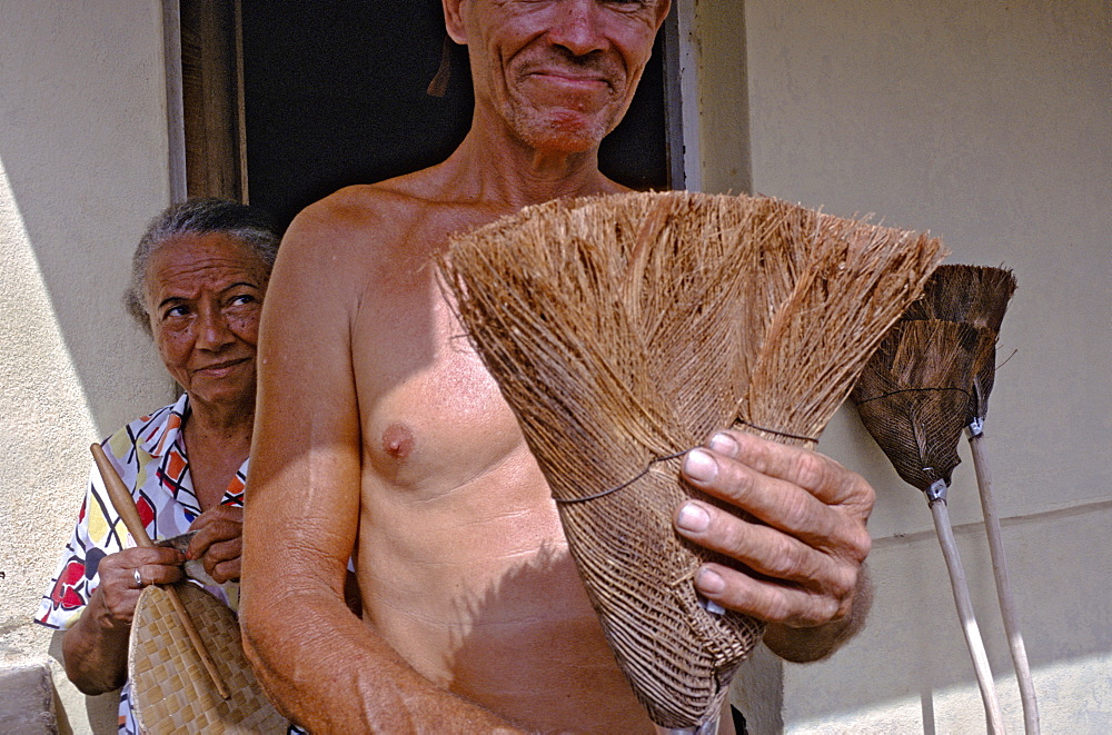 A broom maker displaying one of his handmade, brooms made from coconut fibers in the town of Baracoa in eastern Cuba, Cuba