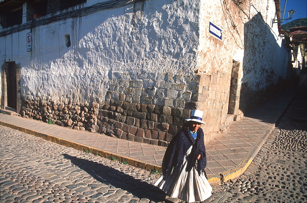 Quechua Indian woman crossing street in front of a colonial building with Incan foundations near the Plaza de Armas, Cuzco, Highlands, Peru