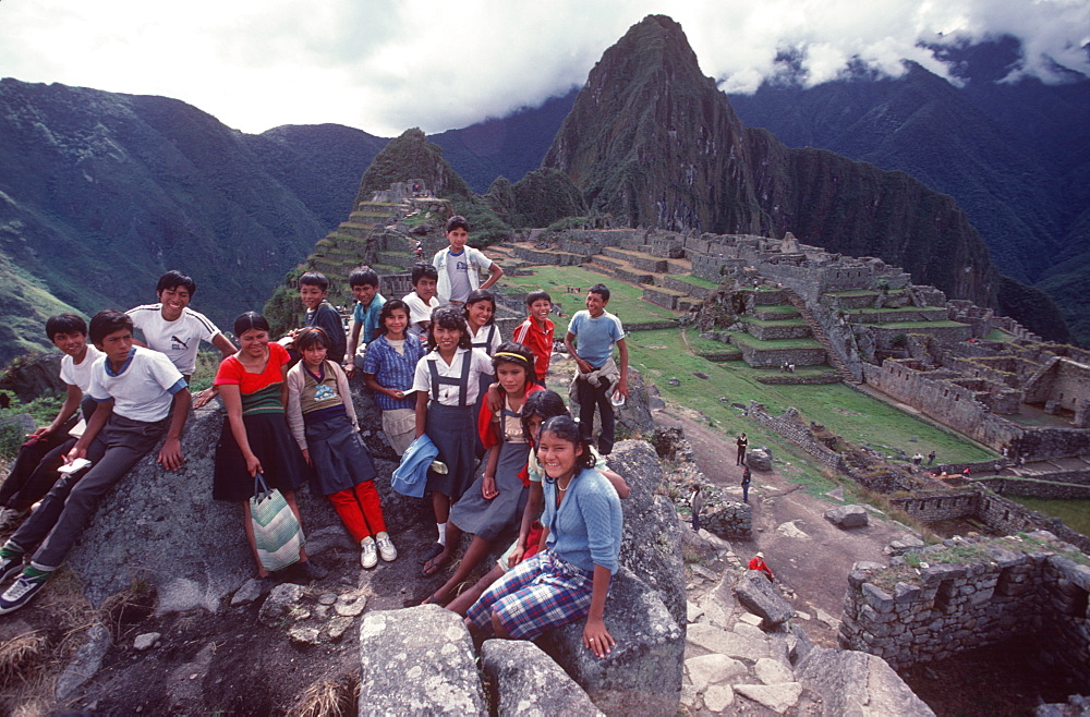 Machu Picchu view of the ancient city with Huayna Picchu Peak above the Rio Urubamba Peruvian school children visiting the site, Highlands, Peru