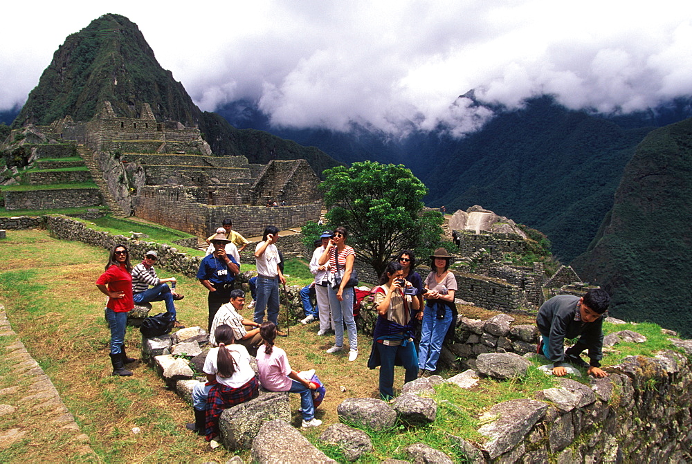 Machu Picchu a family visiting the site sitting below houses, Highlands, Peru