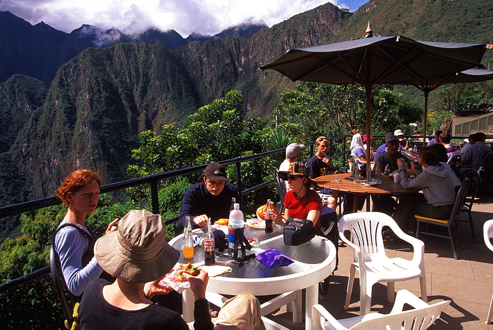 Machu Picchu hikers eating hamburgers in the outdoor cafe after having completed the trek of the Inca Trail, Highlands, Peru