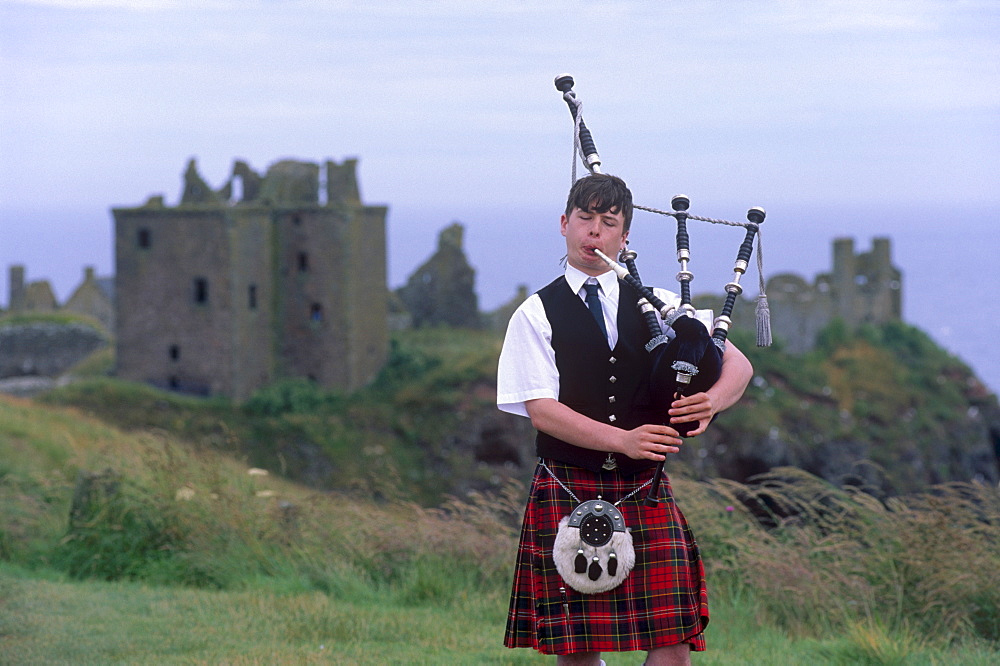 Piper playing, in front of Dunnotar Castle dating from the 14th century, near Stonehaven, Aberdeenshire, Scotland, United Kingdom, Europe