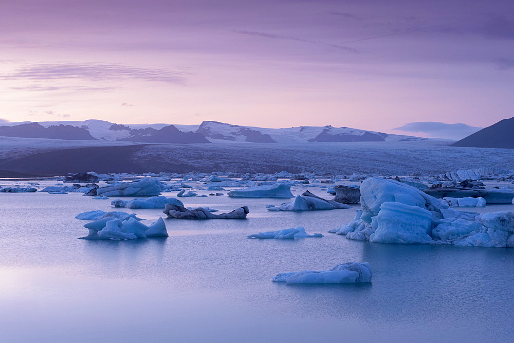 Icebergs in Jokulsarlon glacial lagoon, at dusk, Breidamerkurjokull (Vatnajokull) glacier in the distance, East Iceland, Iceland, Polar Regions