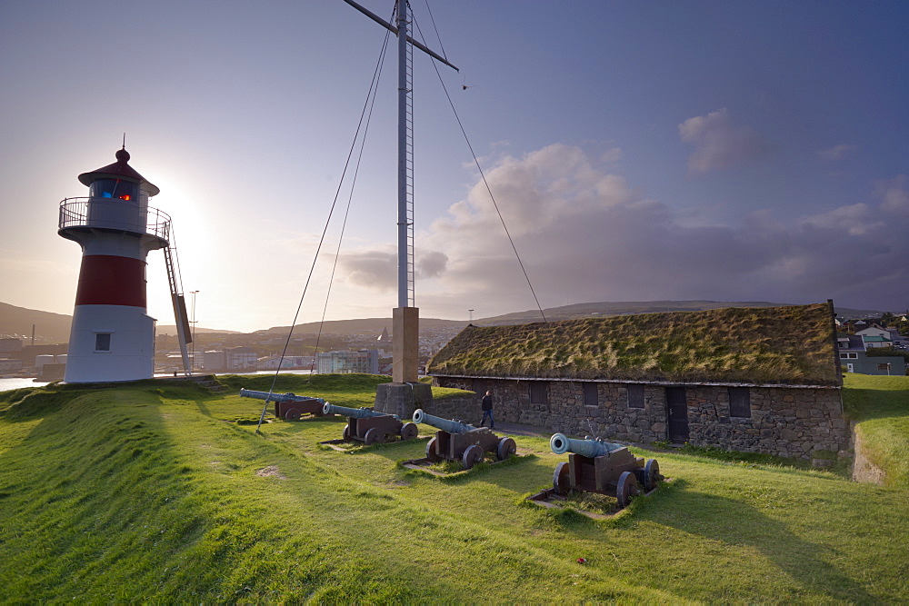 Skansin fort, old fort guarding Torshavn and its harbour (old brass cannons, WW2 british marine guns and lighthouse), Nolsoy in the distance, Torshavn, Streymoy, Faroe islands (Faroes), Denmark, Europe.