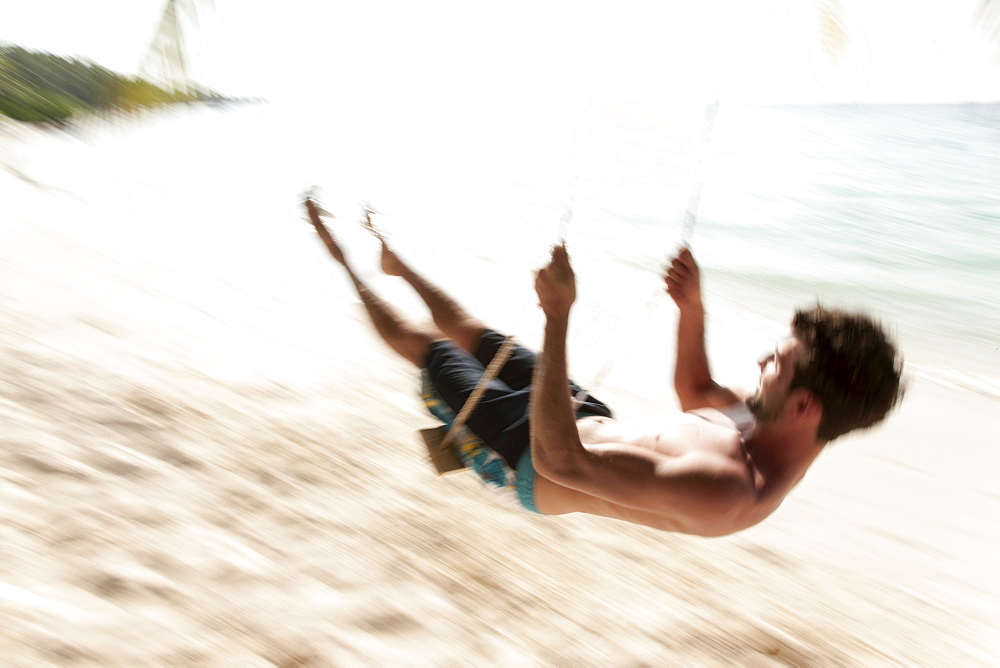 Man swinging on the beach, Kuramathi Island, Ari Atoll, Maldives, Indian Ocean, Asia