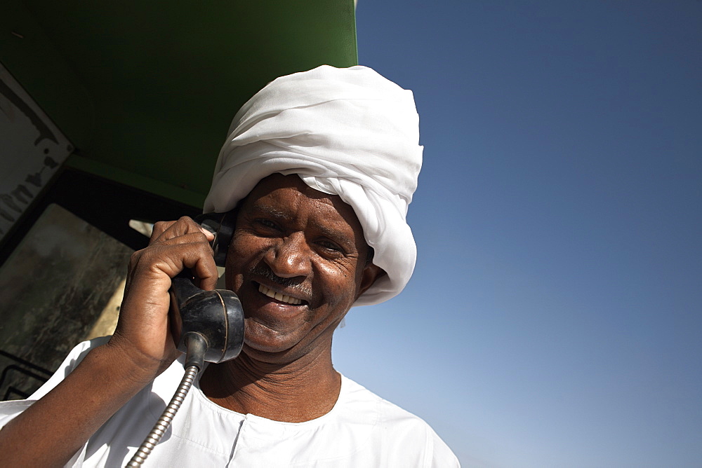 Sudanese man using a telephone in the town of Karima, Sudan, Africa