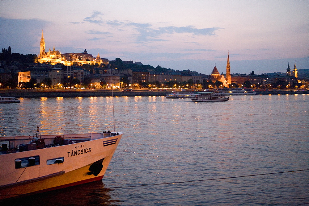 Boats on River Danube with Matyas Church and Castle District illuminated in distance, Budapest, Hungary, Europe