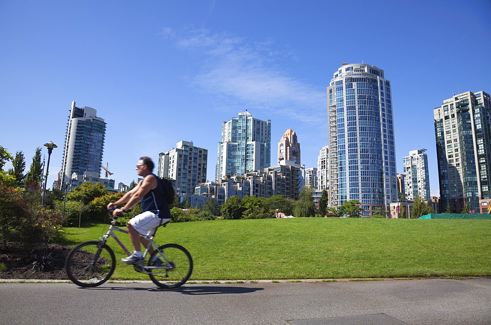 Cyclist passing apartment blocks, False Creek, Vancouver, British Columbia, Canada, North America