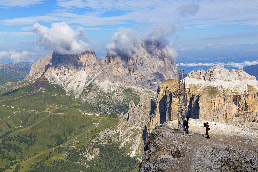 Tourists near cross on Sass Pordoi mountain in the Dolomites near Canazei, with Sassolungo mountains in the distance, Italy, Europe