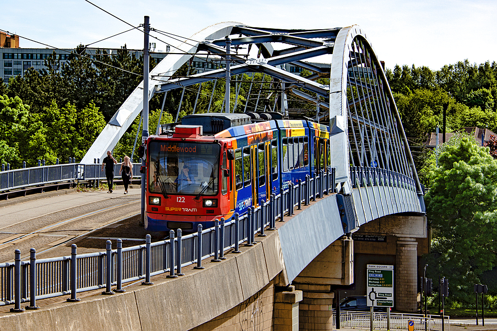 Sheffield tram, known as supertram, passing on an overhead section of track approaching Commercial Street from Park Square Roundabout, Sheaf Valley Quarter,