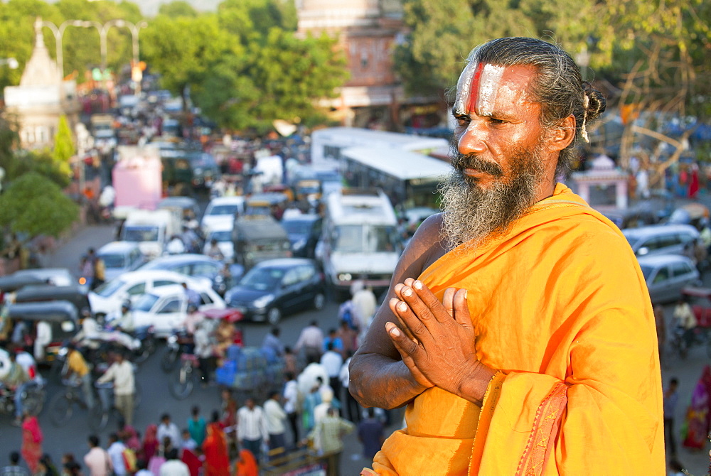 Holy Sadhu meditating high above traffic congestion and street life in the city of Jaipur, Rajasthan, India, Asia