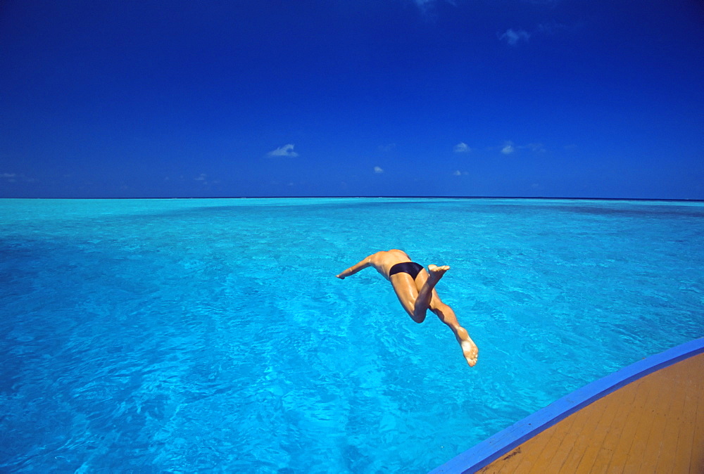 Man jumping into tropical sea from deck, Maldives, Indian Ocean, Asia