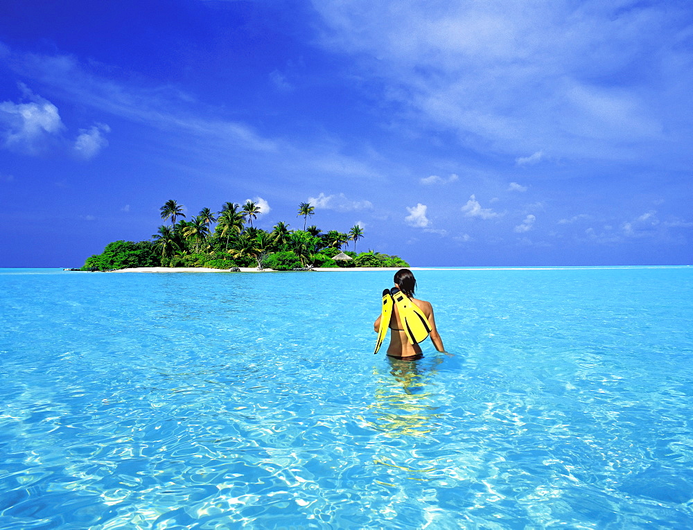 Woman walking with snorkelling equipment to Rihiveli island, Maldives, Indian Ocean, Asia