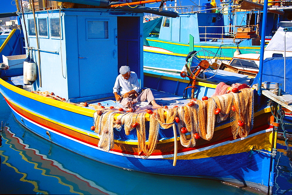 Fisherman knotting a fishing net, Marsaxlokk, Malta, Mediterranean, Europe