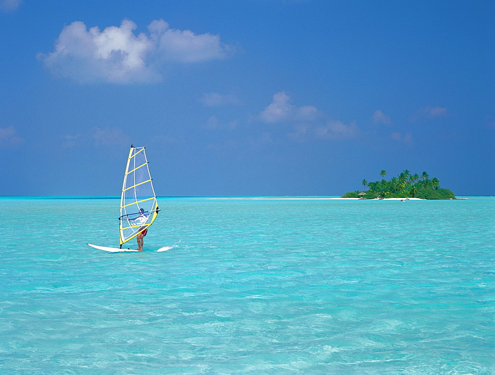 Young man windsurfing near tropical island and lagoon in the Maldives, Indian Ocean